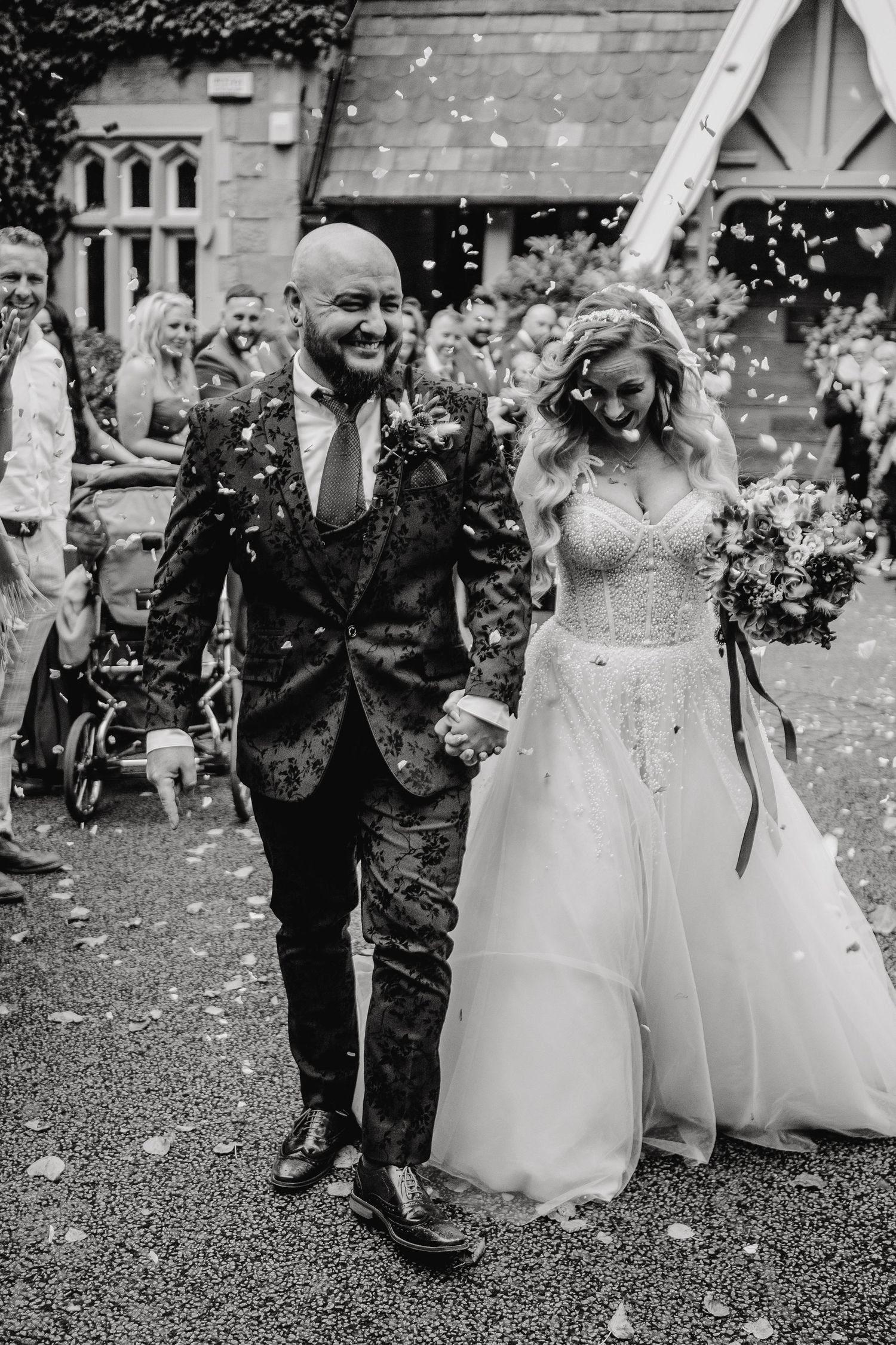 Black and white photo of wedding guests throwing confetti outside a church.