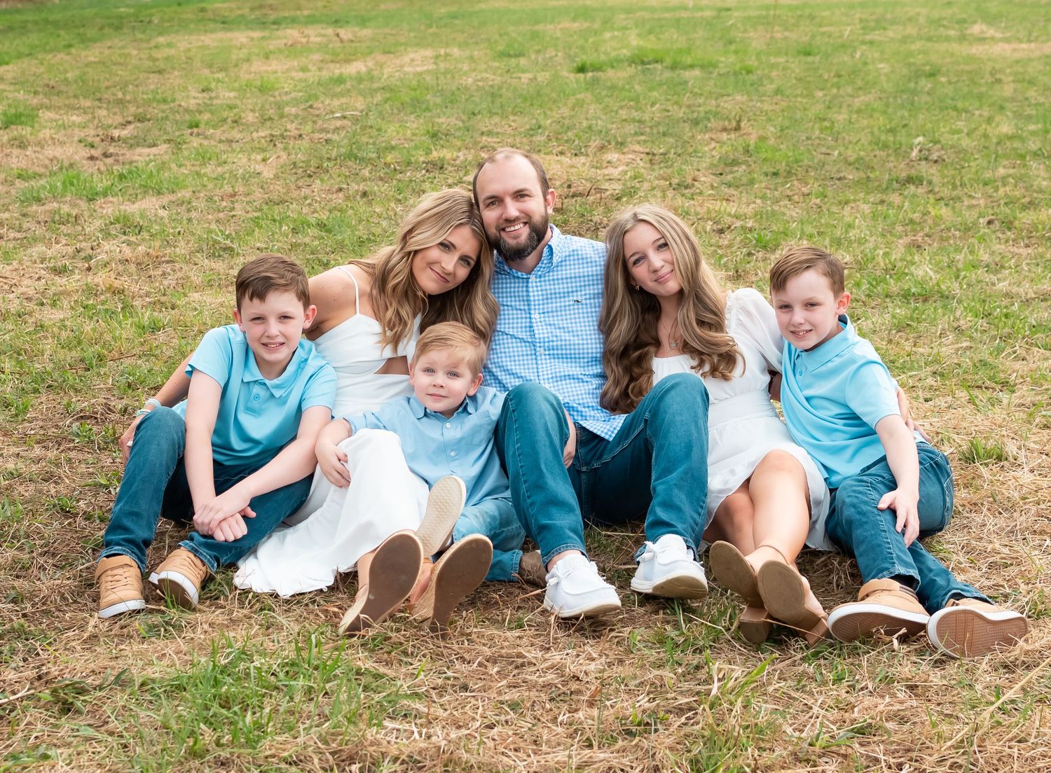 family photo posed with multiple people in a grass field