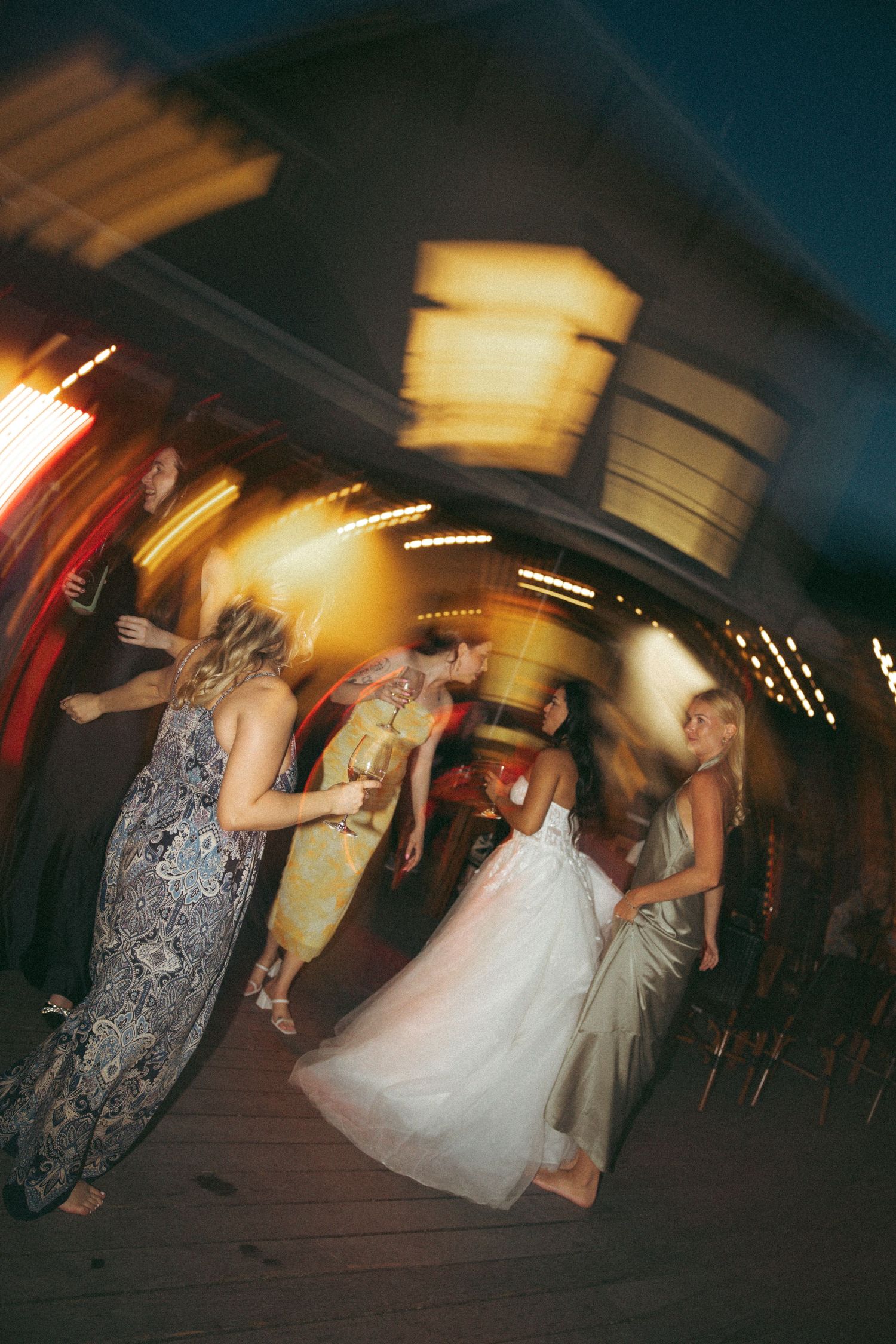 Guests dance together at a wedding reception with motion blur and warm lighting effects.