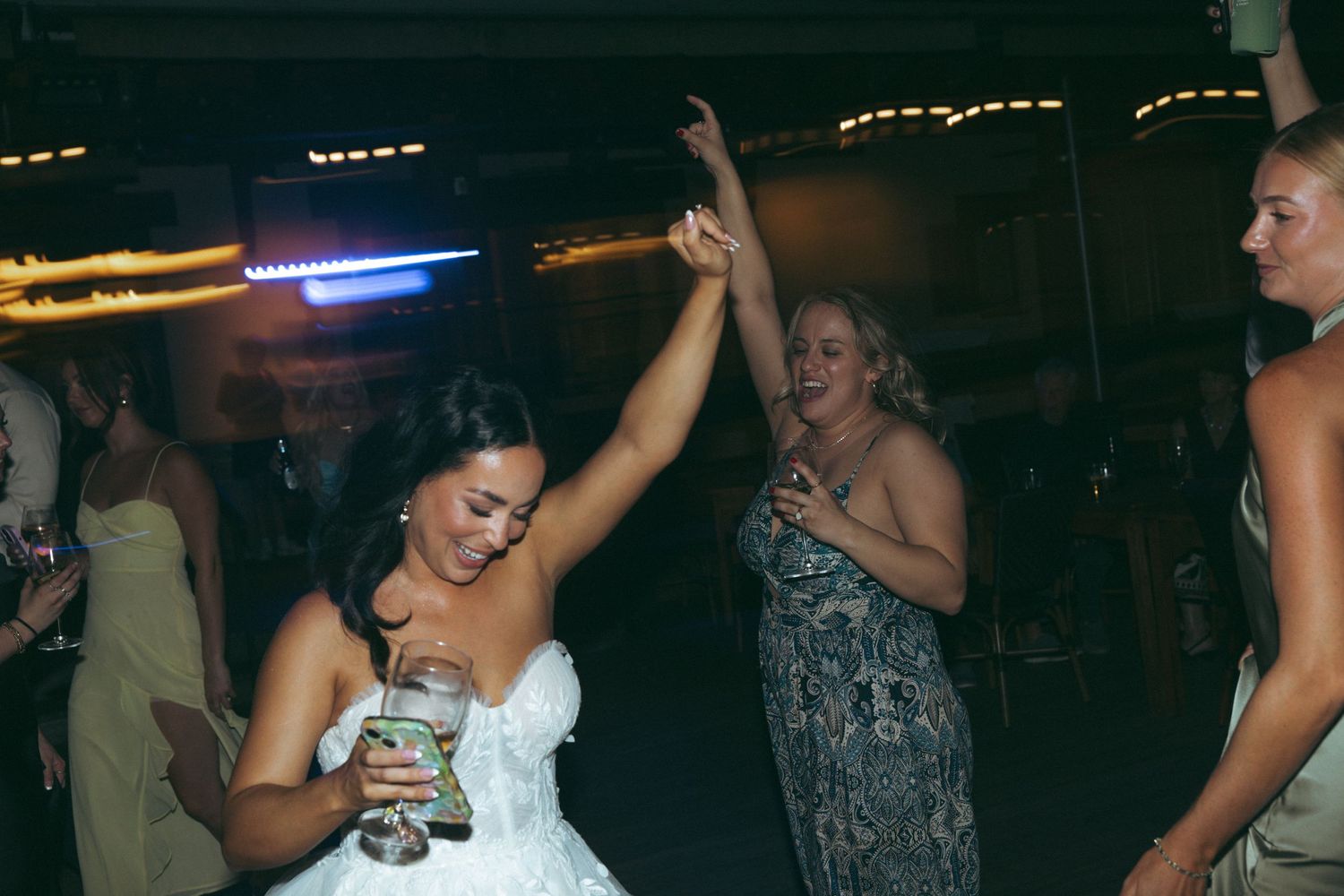 Wedding celebration on dance floor with festive lighting and dancing guests.