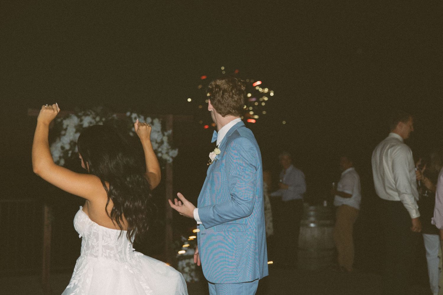 Joyful dancing moment captured during wedding celebration with sparklers.