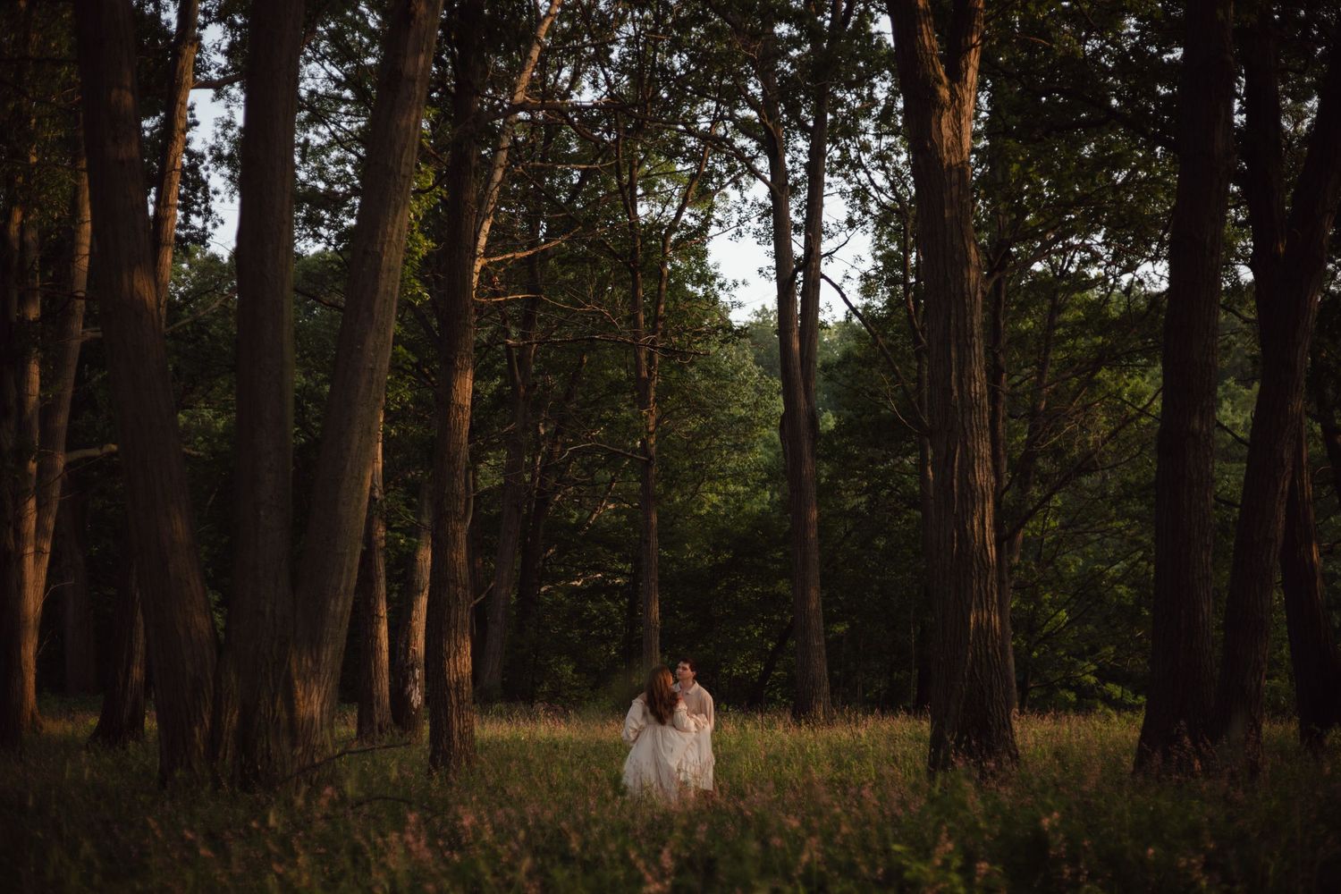 Goth couple embracing a romantic moment together during their moody candlelit engagement session.