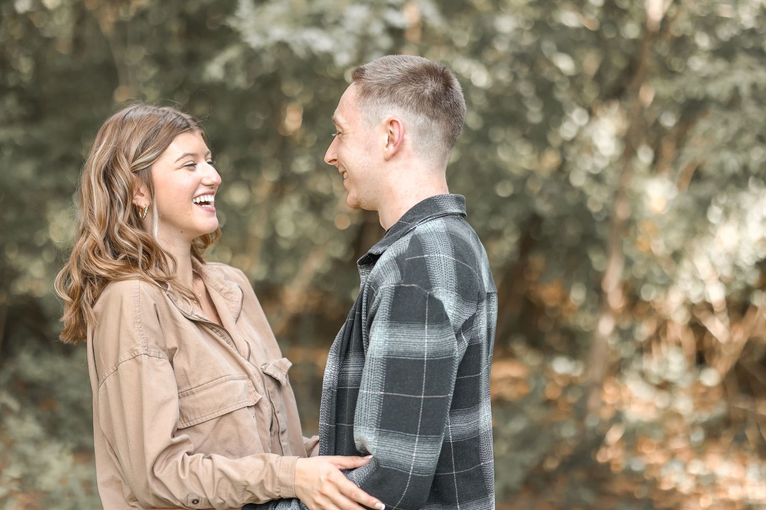 Couple sharing an intimate laughing moment while wearing coordinated fall outfits.