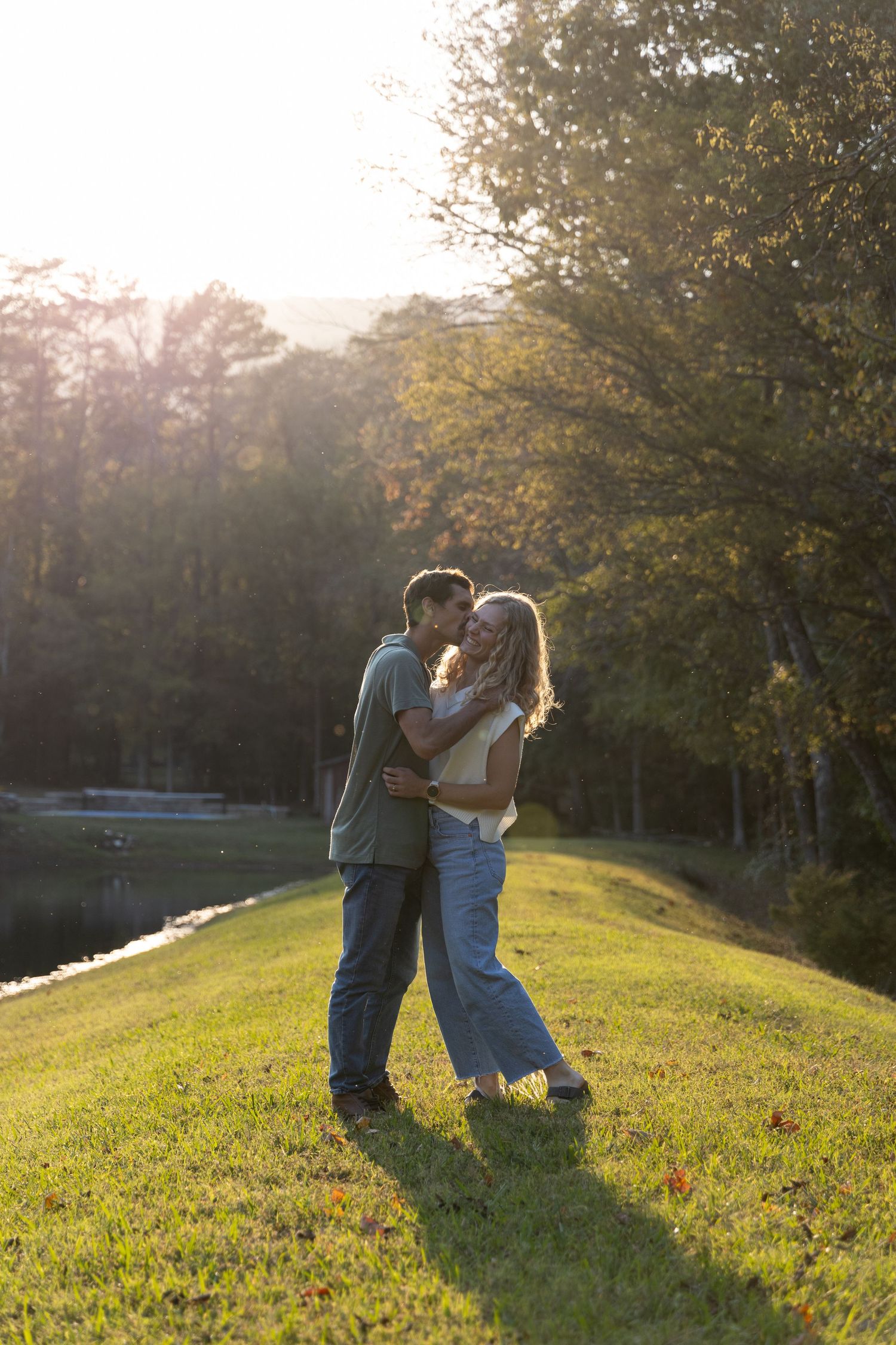 A romantic sunset moment shared between two people on a grassy hillside.