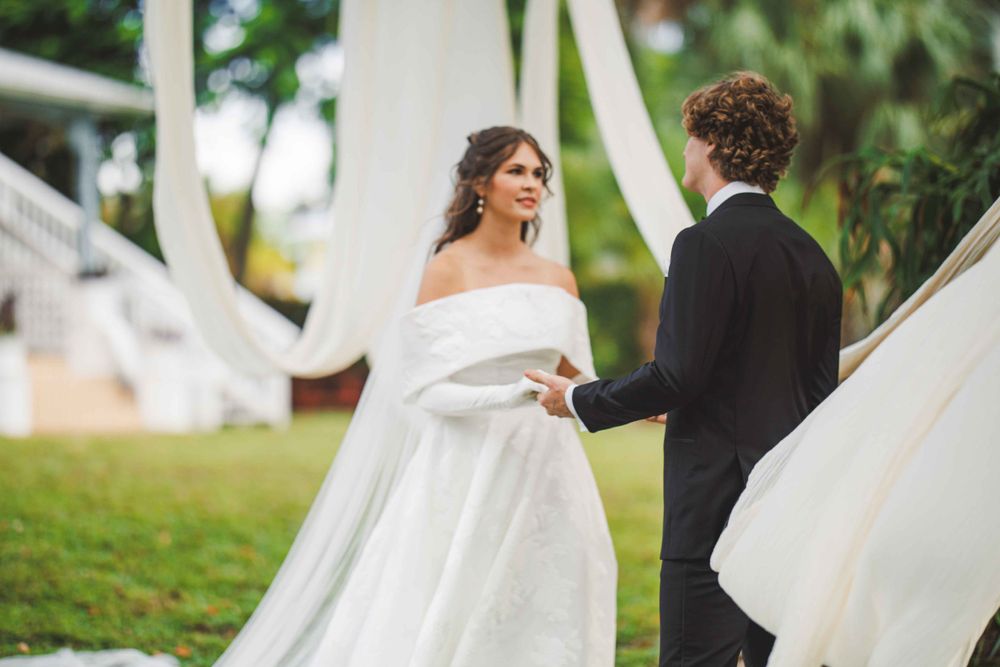Wedding couple sharing a moment outdoors with flowing white dress and decorative fabric.