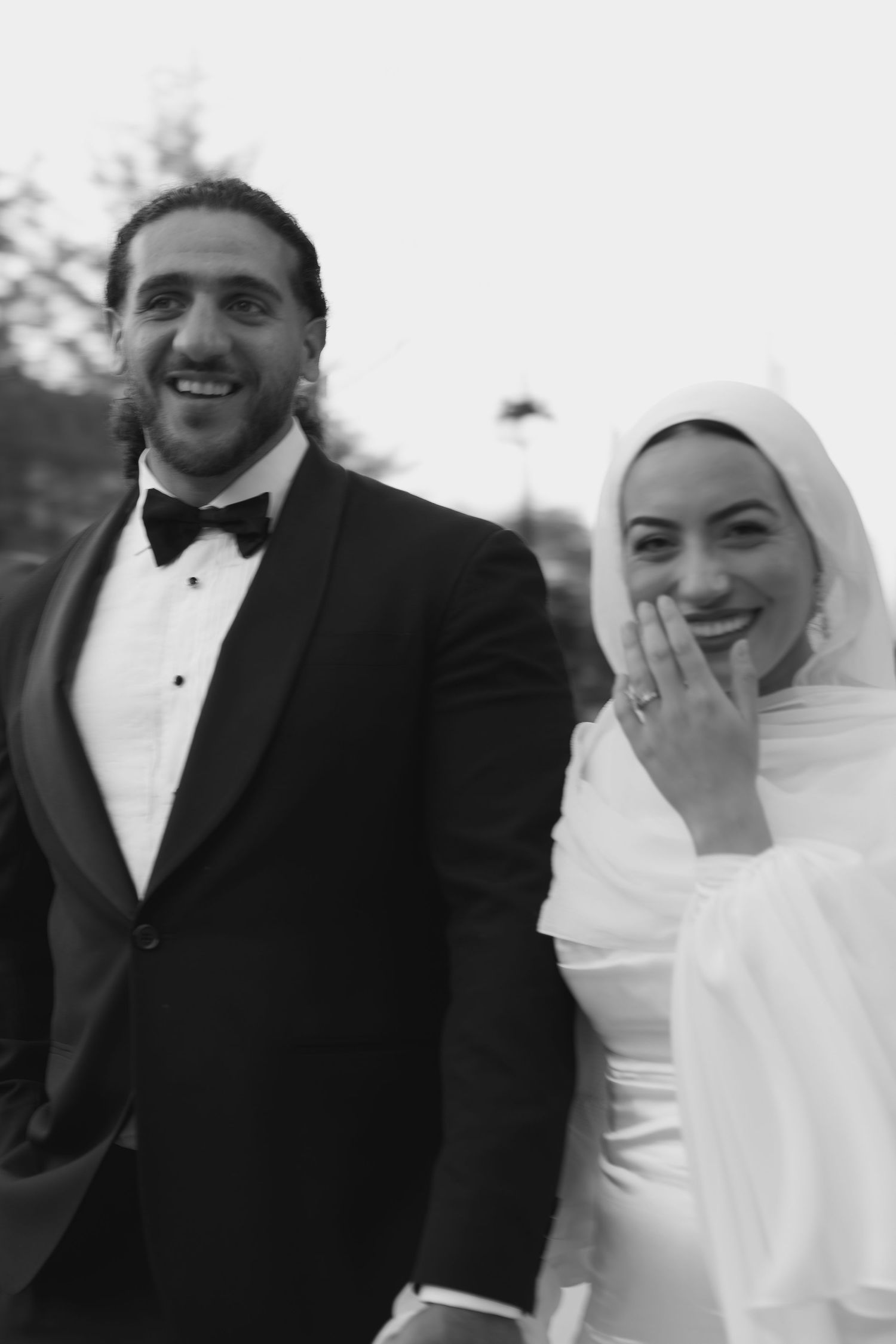 Newlyweds stand together during outdoor wedding ceremony with bride holding white bouquet.