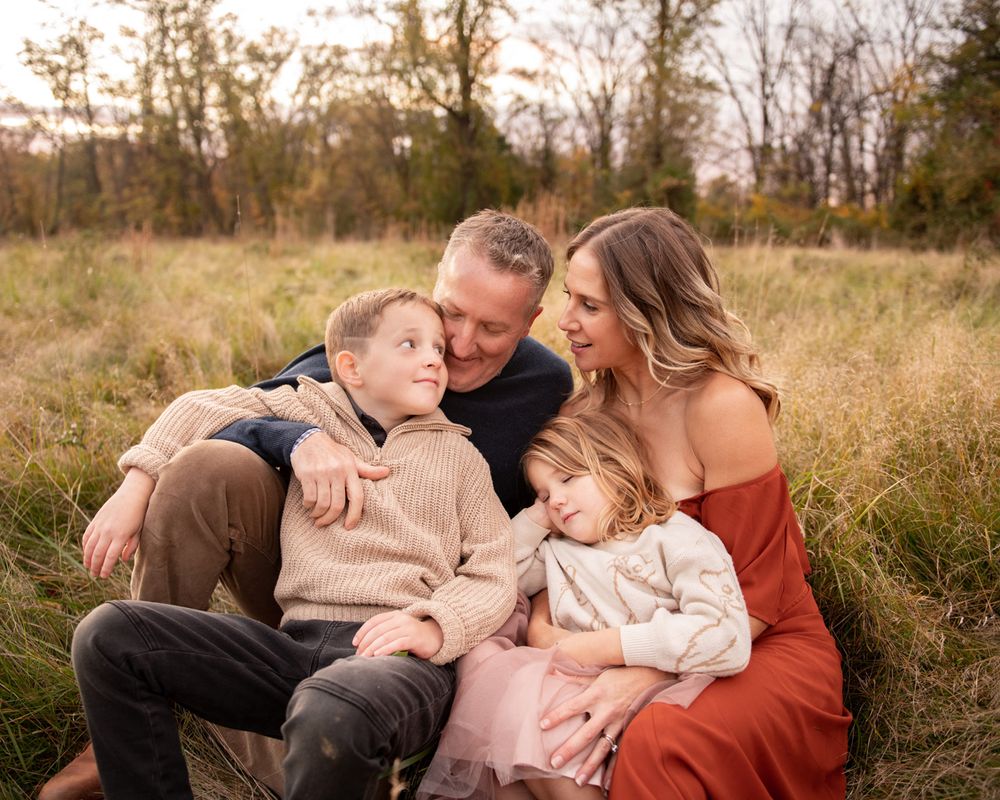 An intimate family portrait shows tender moments between parents and children in a fall setting.