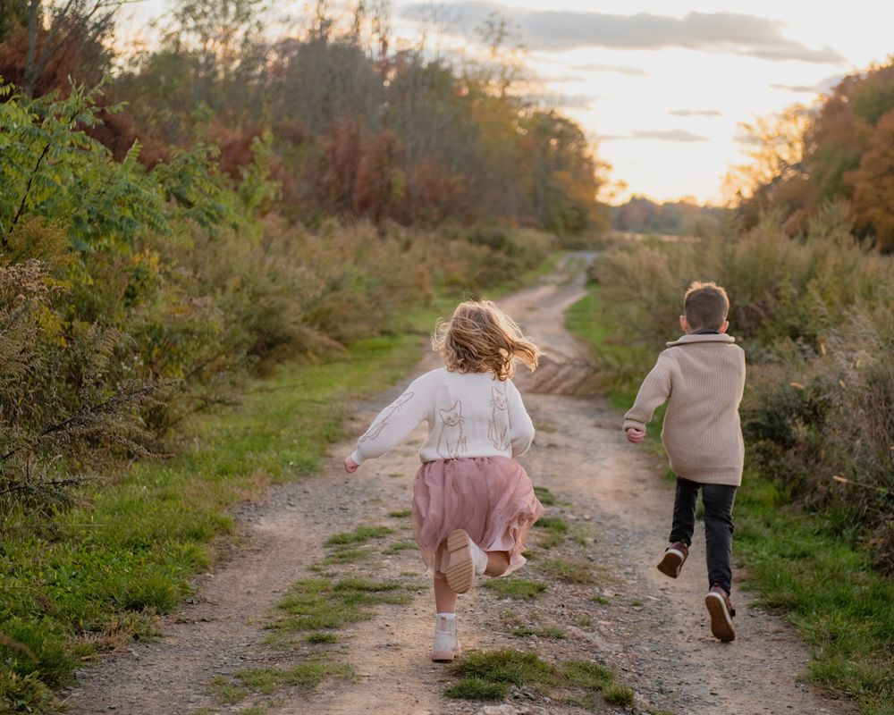 Two children running and playing together on a scenic trail during golden hour.