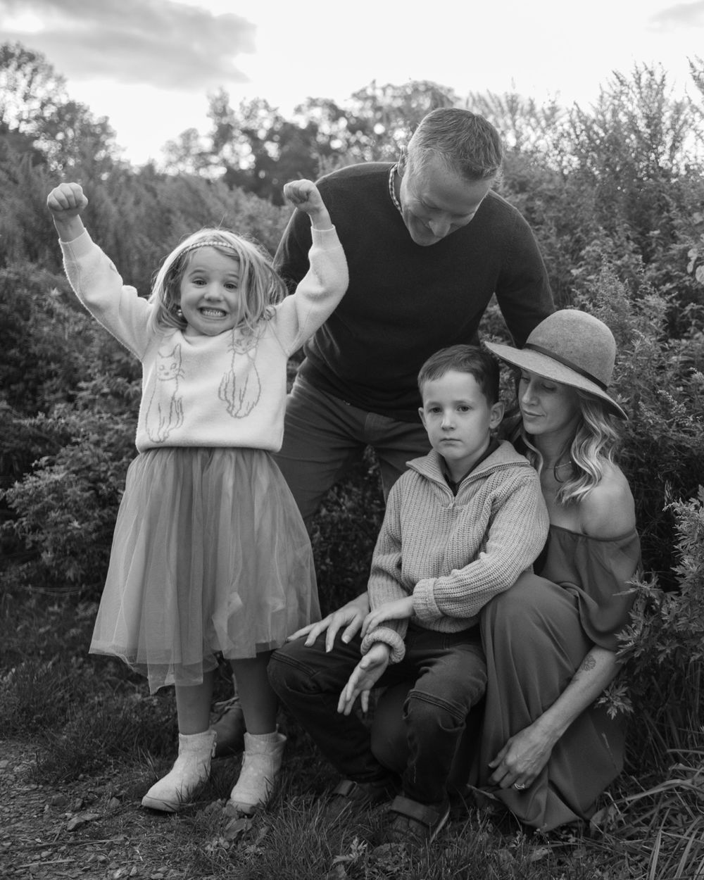 A black and white portrait of a family sharing a joyful moment outdoors.