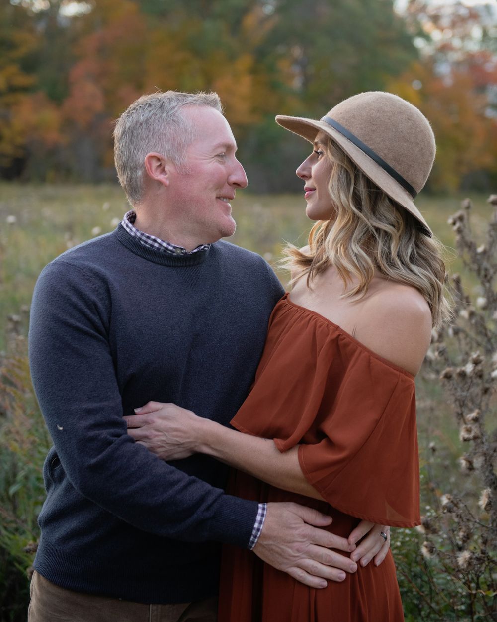 A romantic couple in autumn attire share an intimate moment in a natural setting.