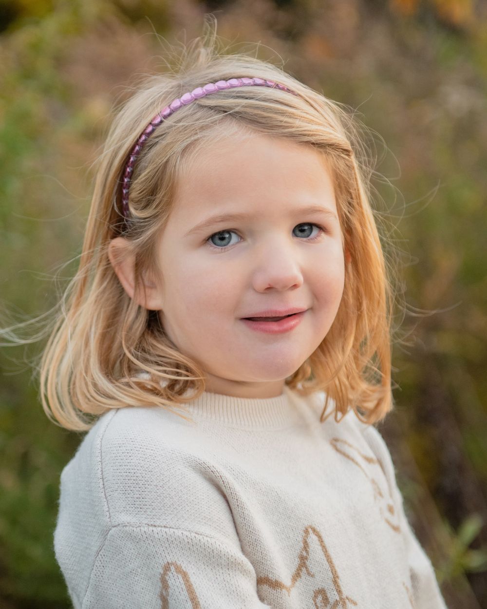 A close up portrait with autumn foliage in soft focus background.