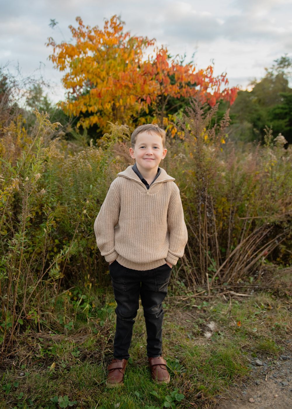 A scenic fall portrait with vibrant orange trees and tall grass in the background.