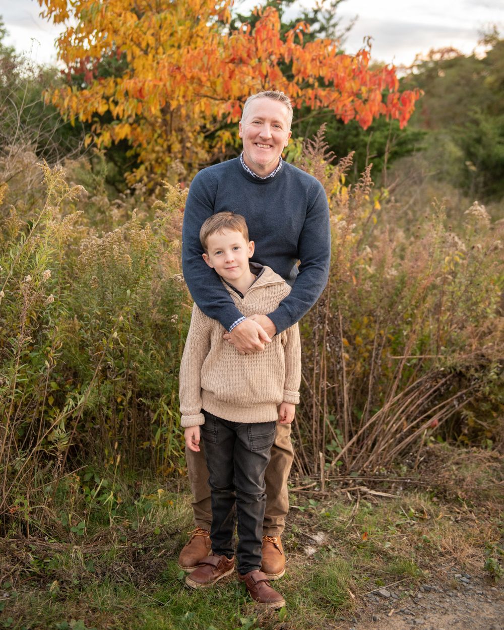 An autumn outdoor portrait against colorful foliage and natural brush.
