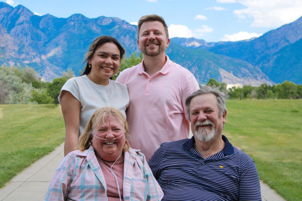 Group portrait against majestic mountain backdrop on a sunny day in a grassy field.