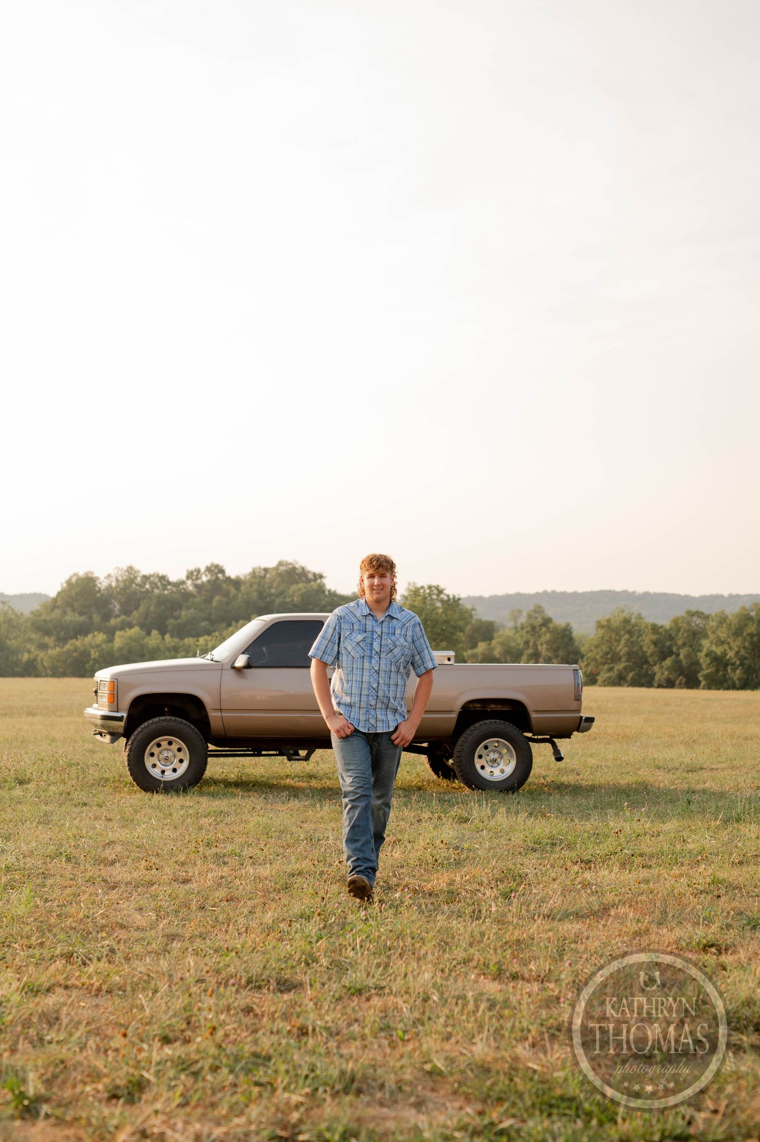 A country lifestyle portrait with a lifted GMC pickup truck in a grassy field.