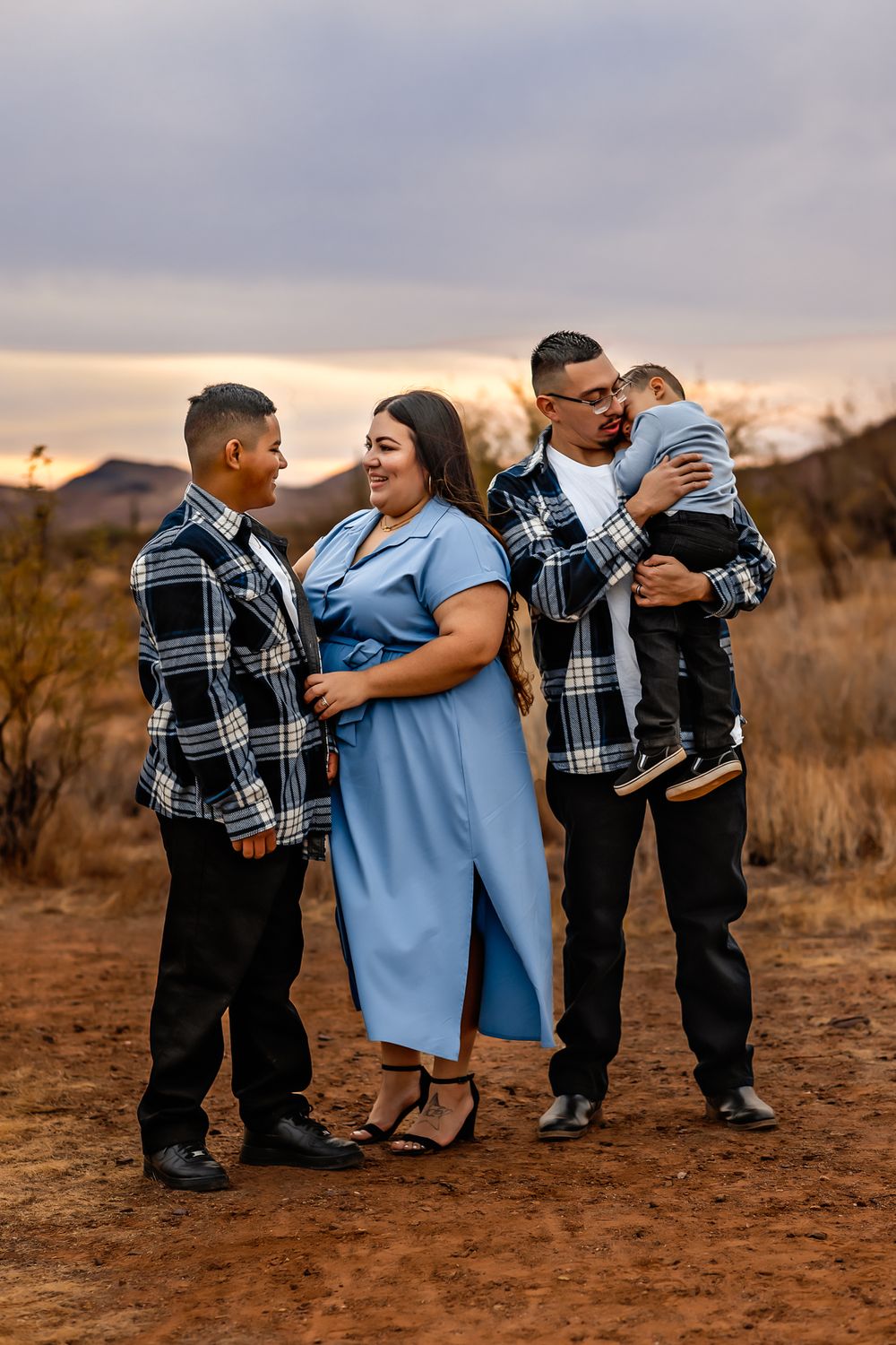 Family photos outdoors at dusk wearing coordinated blue and plaid outfits for their maternity session at Apache Wash Trailhead