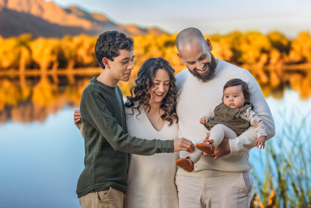Family moment by a Salt River with mountains glowing in golden sunset light for their family photoshoot in Mesa Arizona