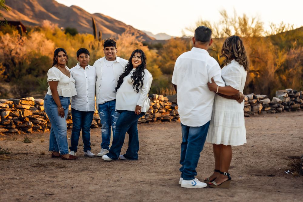 Family poses together outdoors against desert mountains during sunset golden hour photography session.