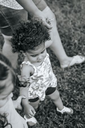 Baby in floral outfit crawling and playing on grass in black and white photo series.