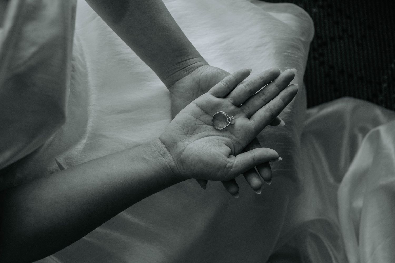A black and white close-up of hands holding a delicate ring.