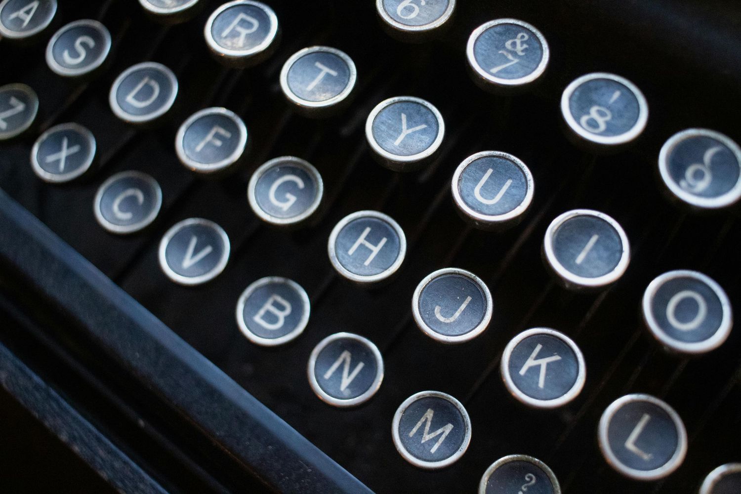 Close-up view of vintage typewriter keys showing circular metal buttons with black background.