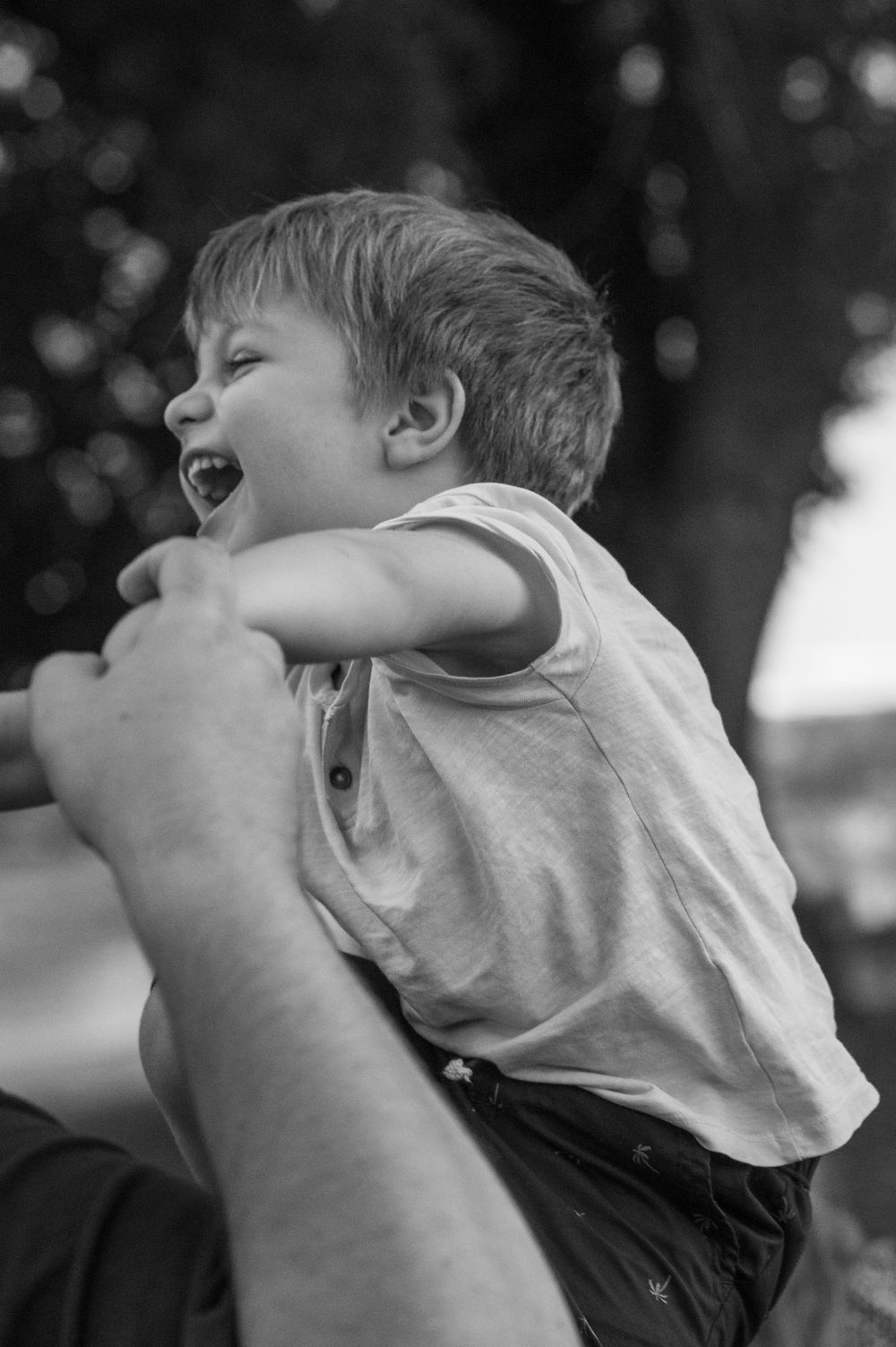 little boy laughing while playing with his father in the park