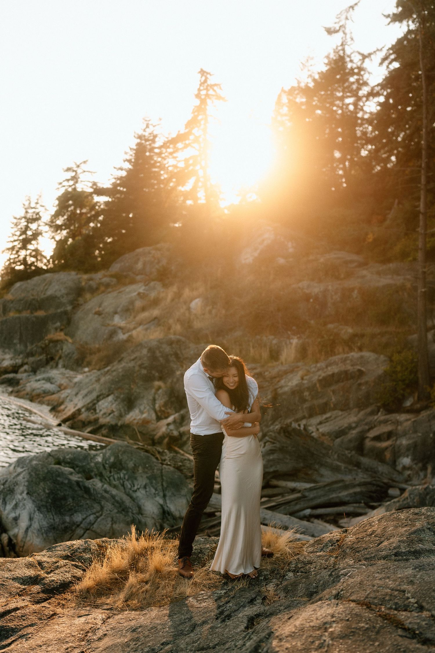 A girl beaming with joy with her arms up during golden hour in Tofino, British Columbia.