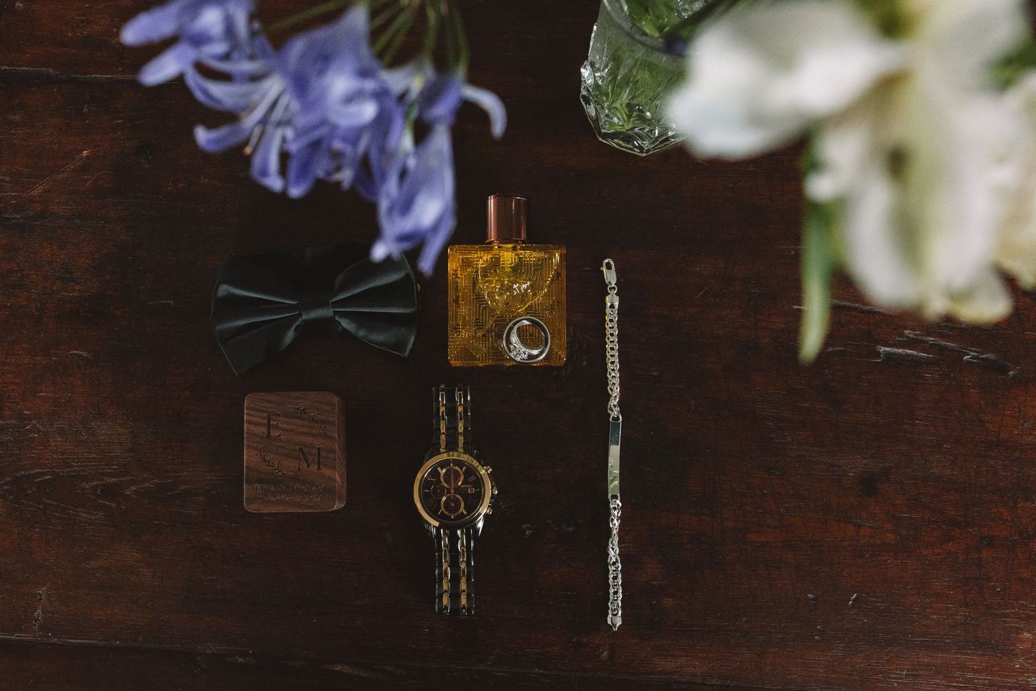 Vintage keys, flower petals, and decorative items arranged on a dark wooden surface with a warm, rustic aesthetic.