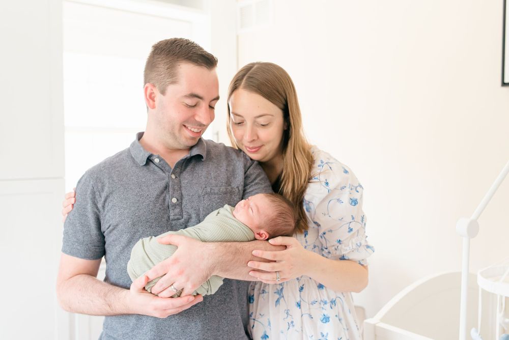 Monmouth County NJ newborn photography — parents gazing lovingly at their sleeping baby.