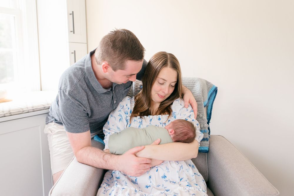 Soft natural light portrait of newborn with parents in Fair Haven, NJ—luxury family photography in Monmouth County.