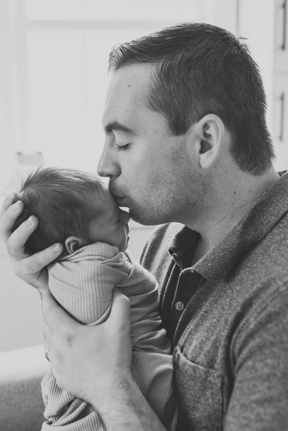 Black and white photo of father kissing his newborn son taken in Fair Haven NJ by a Monmouth County lifestyle photographer.