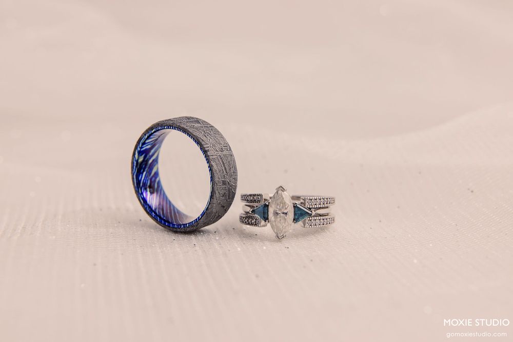 Wedding rings nestled in soft white sand create an elegant and romantic beach wedding detail shot.