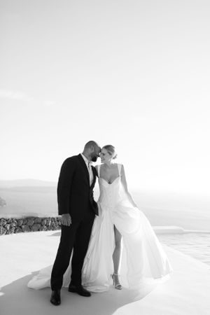 A black and white wedding portrait of a couple sharing an intimate moment on a white terrace.