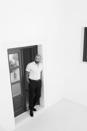 Minimalist black and white architectural photo showing figure framed in traditional Greek doorway.