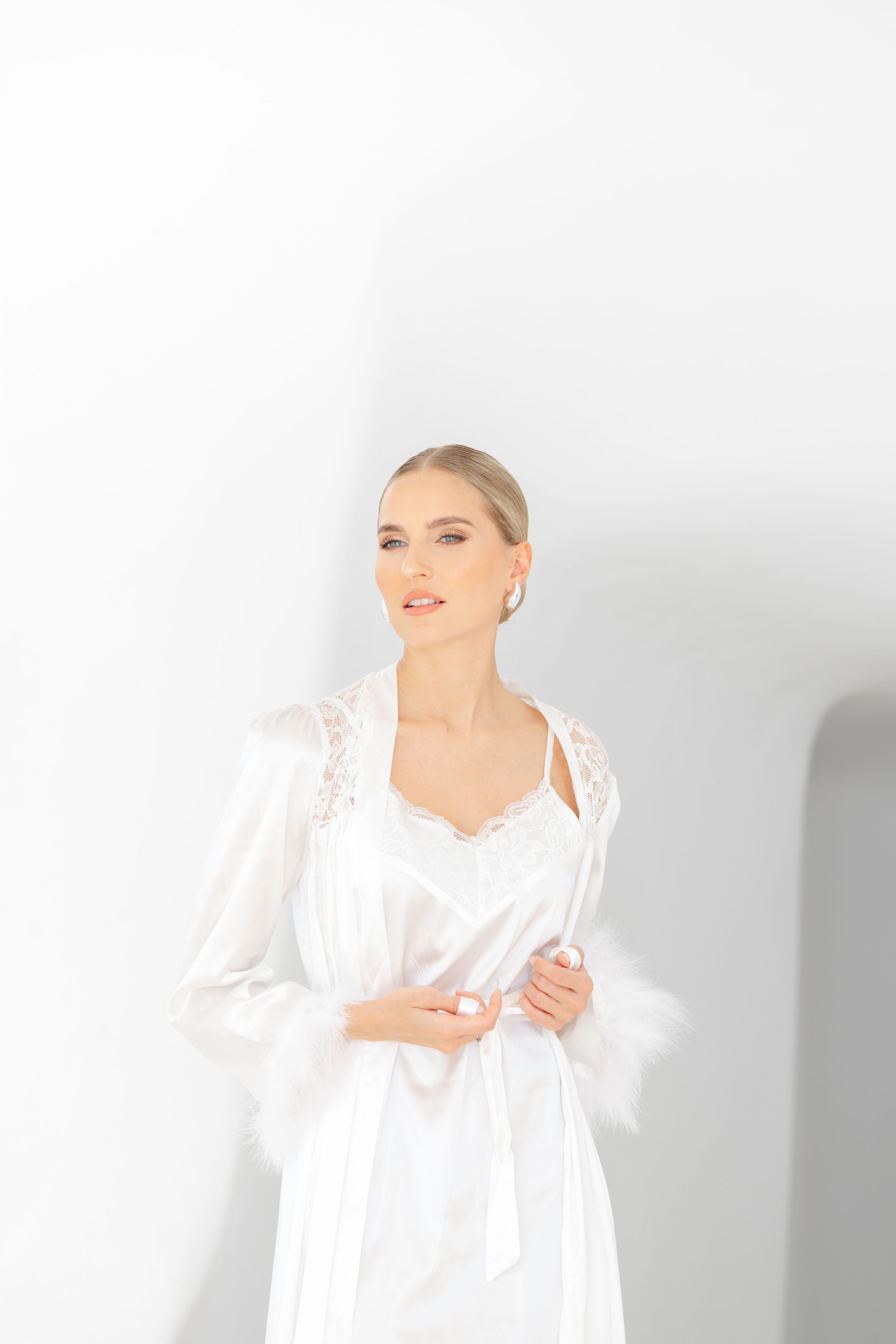 Elegant white lace robe photographed against a minimalist white background in a bridal boudoir setting.