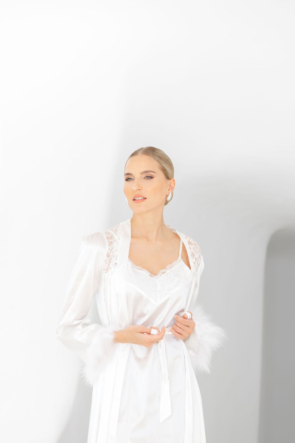Elegant white lace robe photographed against a minimalist white background in a bridal boudoir setting.