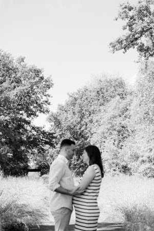 Black and white portrait of couple embracing on nature trail.