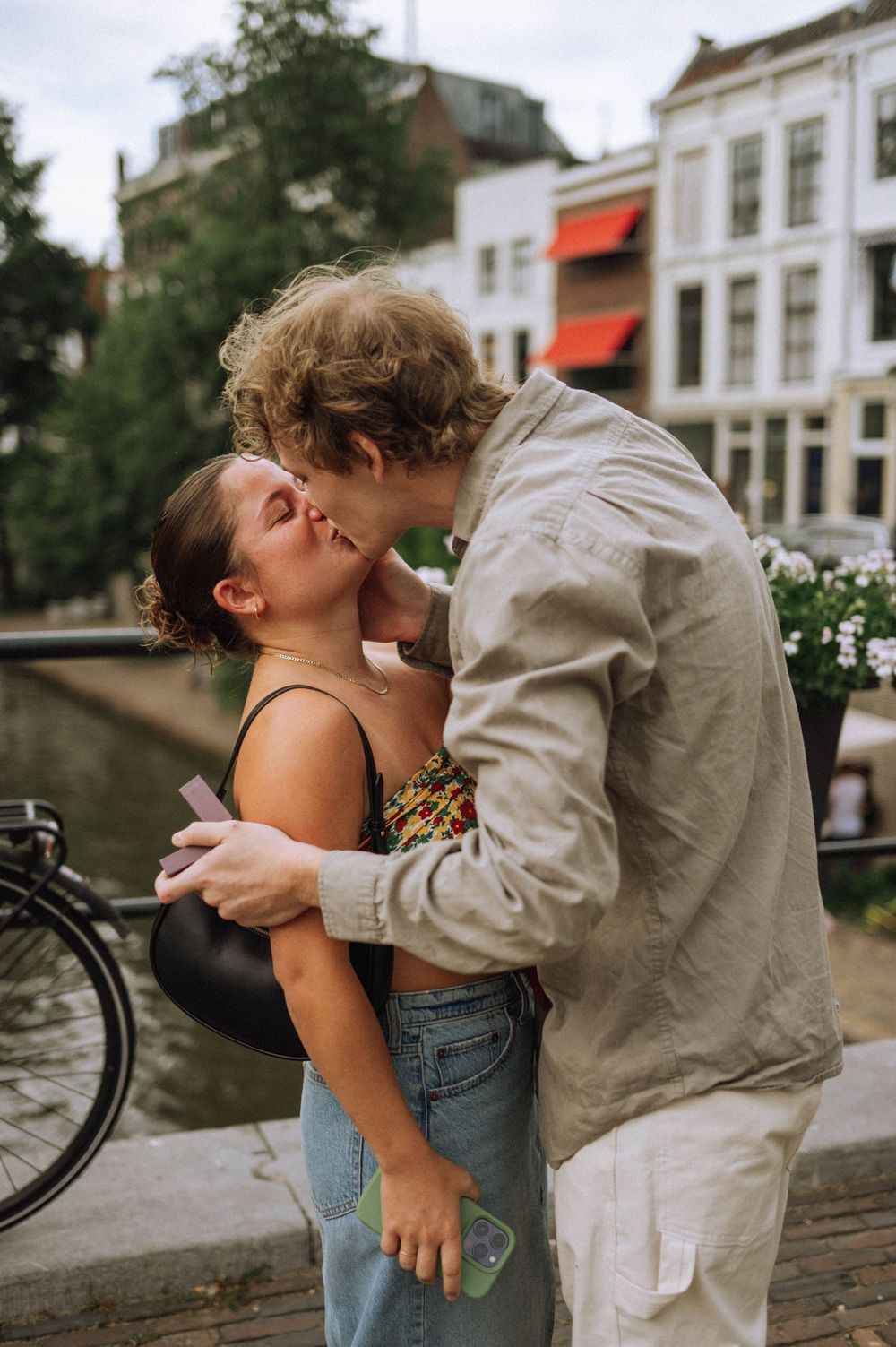 A tender moment between a couple on a cobblestone street with traditional European architecture.