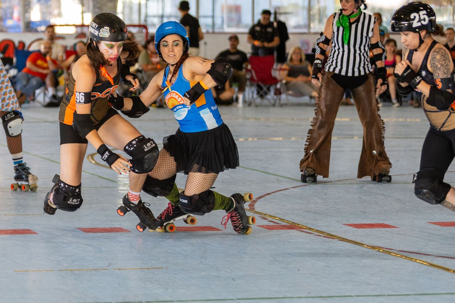 Roller derby athletes in protective gear compete during an outdoor match at sunset.