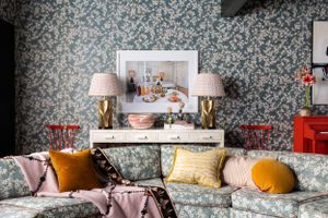 Elegant living space featuring floral wallpaper, plush seating with colorful pillows, and symmetrical table lamps.