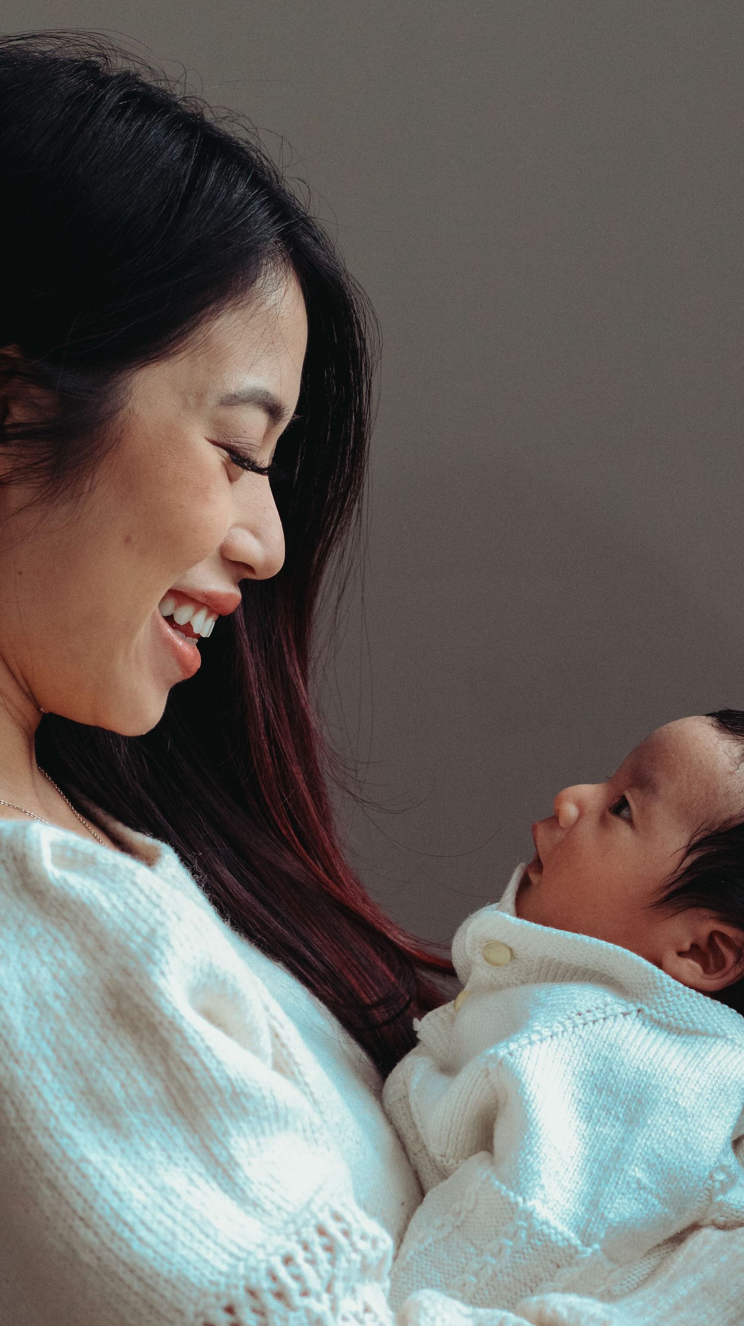 newborn and mom look at each photographed from the side angle