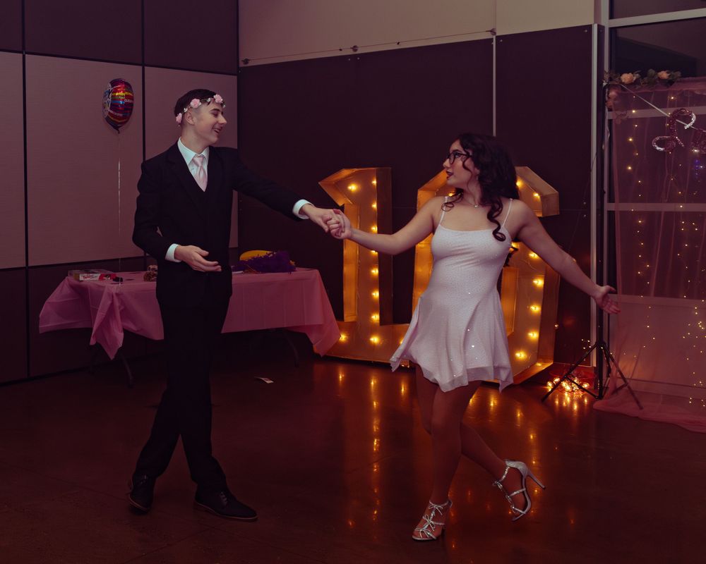 Two people dance together at a reception with illuminated marquee letters providing warm lighting in the background.