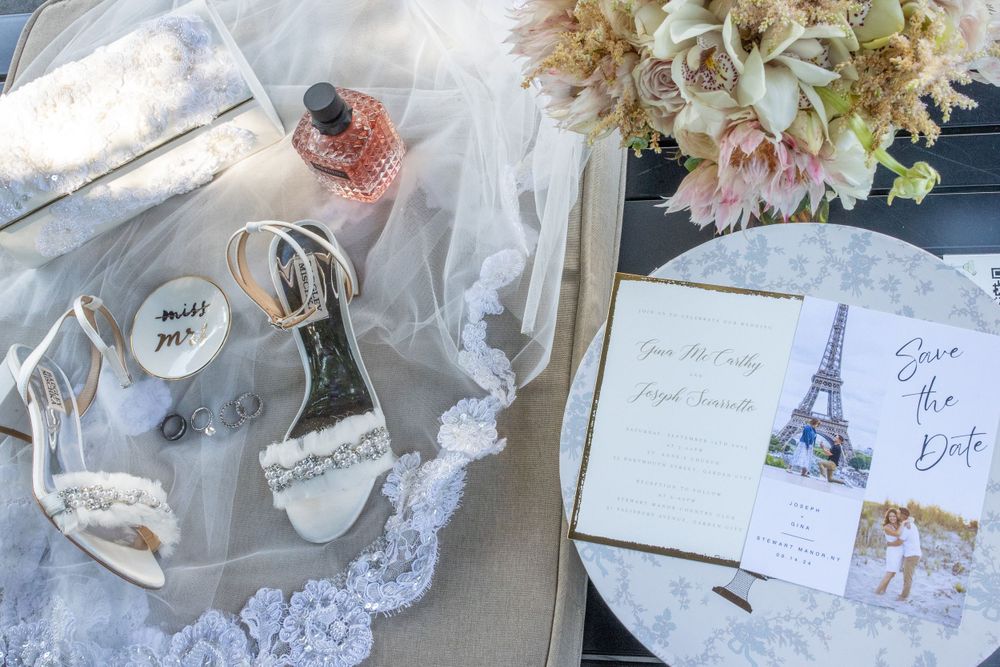 Flat lay of wedding details including bridal shoes, Save the Date cards, bouquet, and accessories.