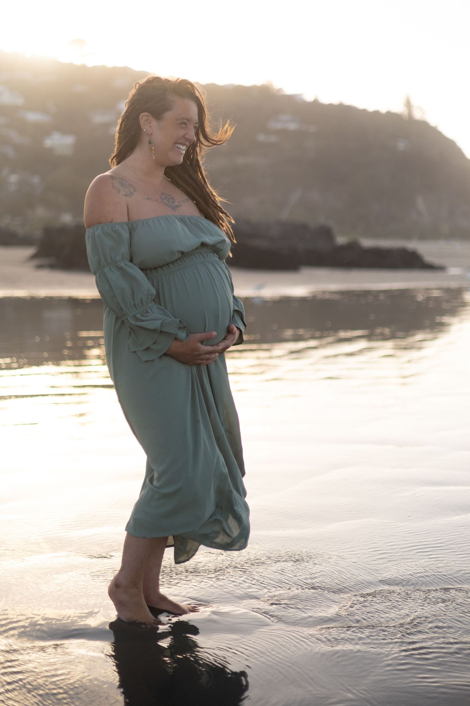 Pregnant mother holding bump at the beach during maternity photoshoot
