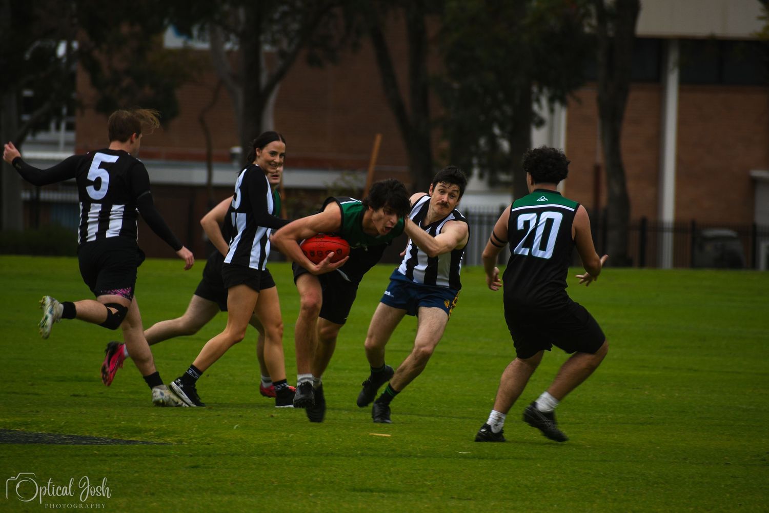 Australian rules football players compete for the ball during a match on a grass field.