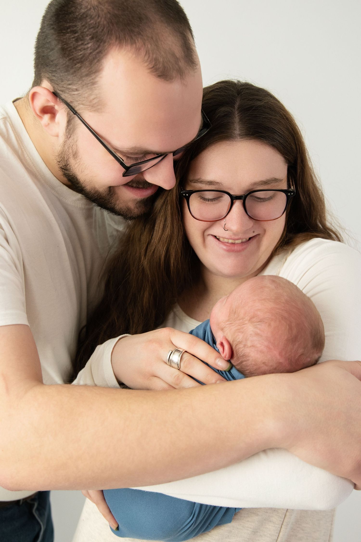 Mom and dad holding their newborn baby in a warm, intimate family portrait.