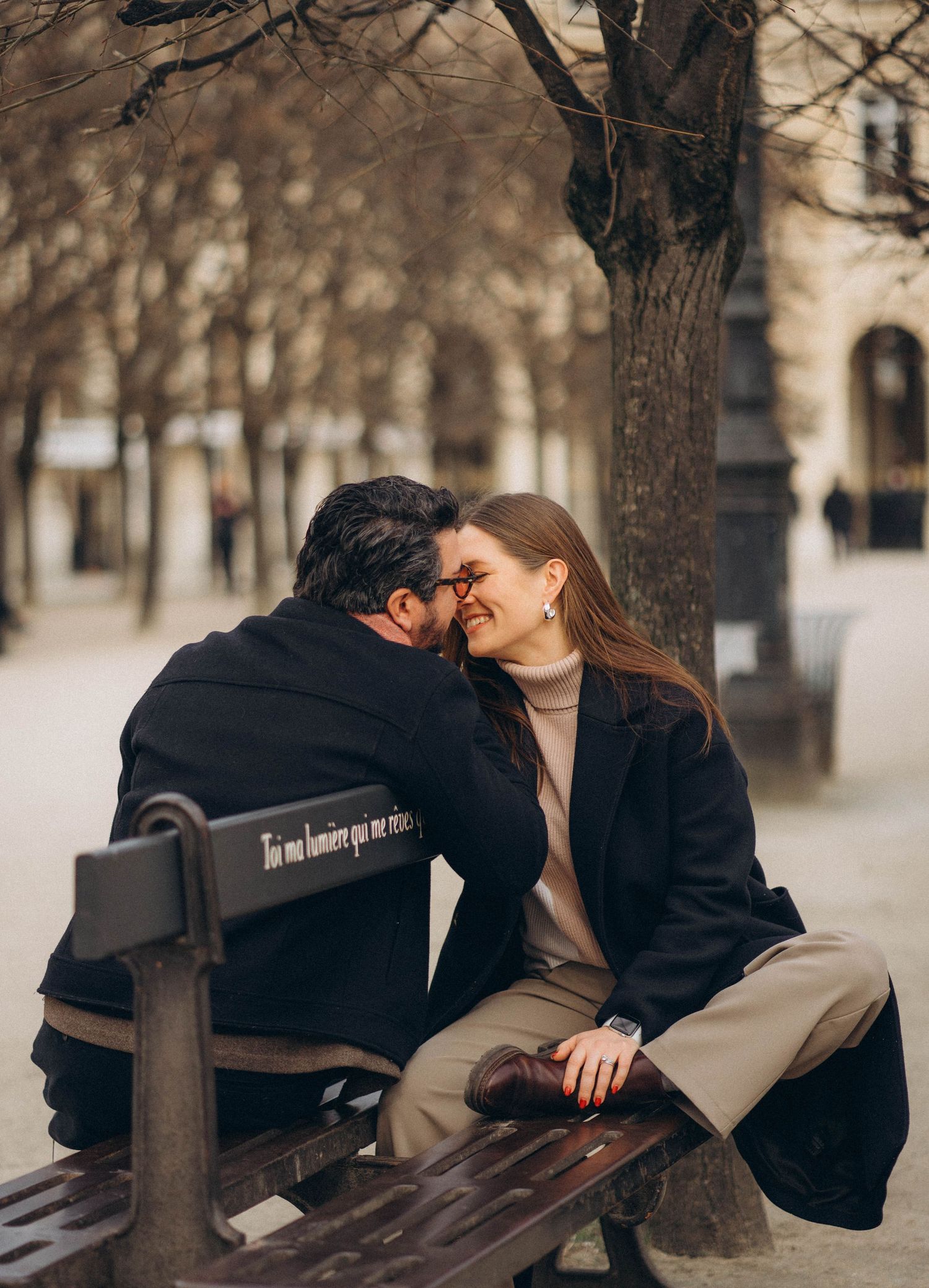A couple sharing an intimate moment on a park bench during autumn.