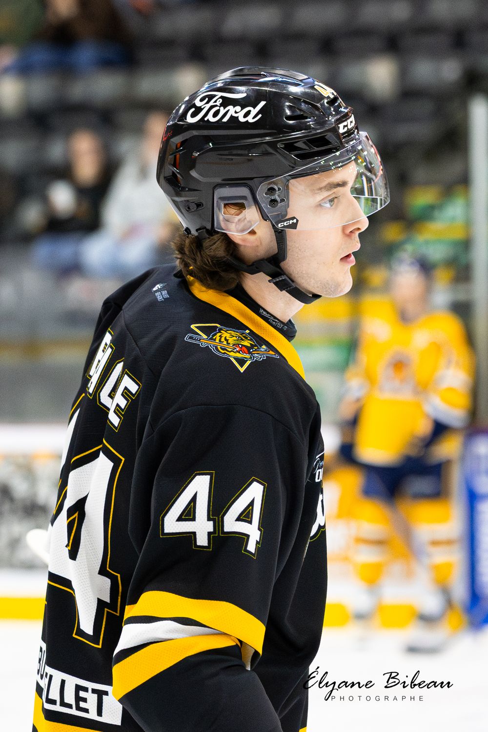 Hockey player wearing black jersey with number 44 and Ford logo on helmet.