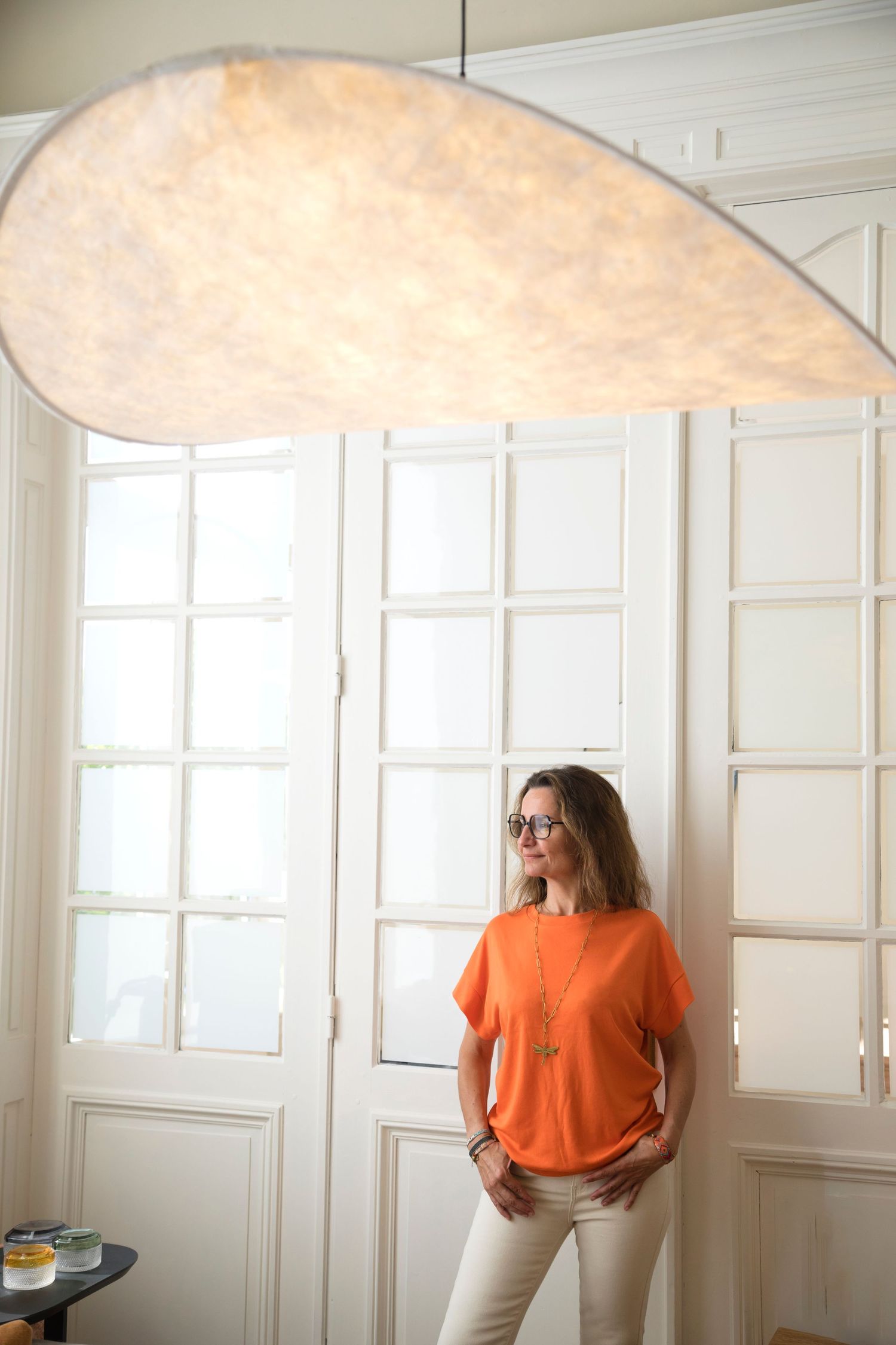 Une entrepreneuse portant un haut à imprimé floral est assise à un bureau dans un espace de bureau moderne et lumineux.