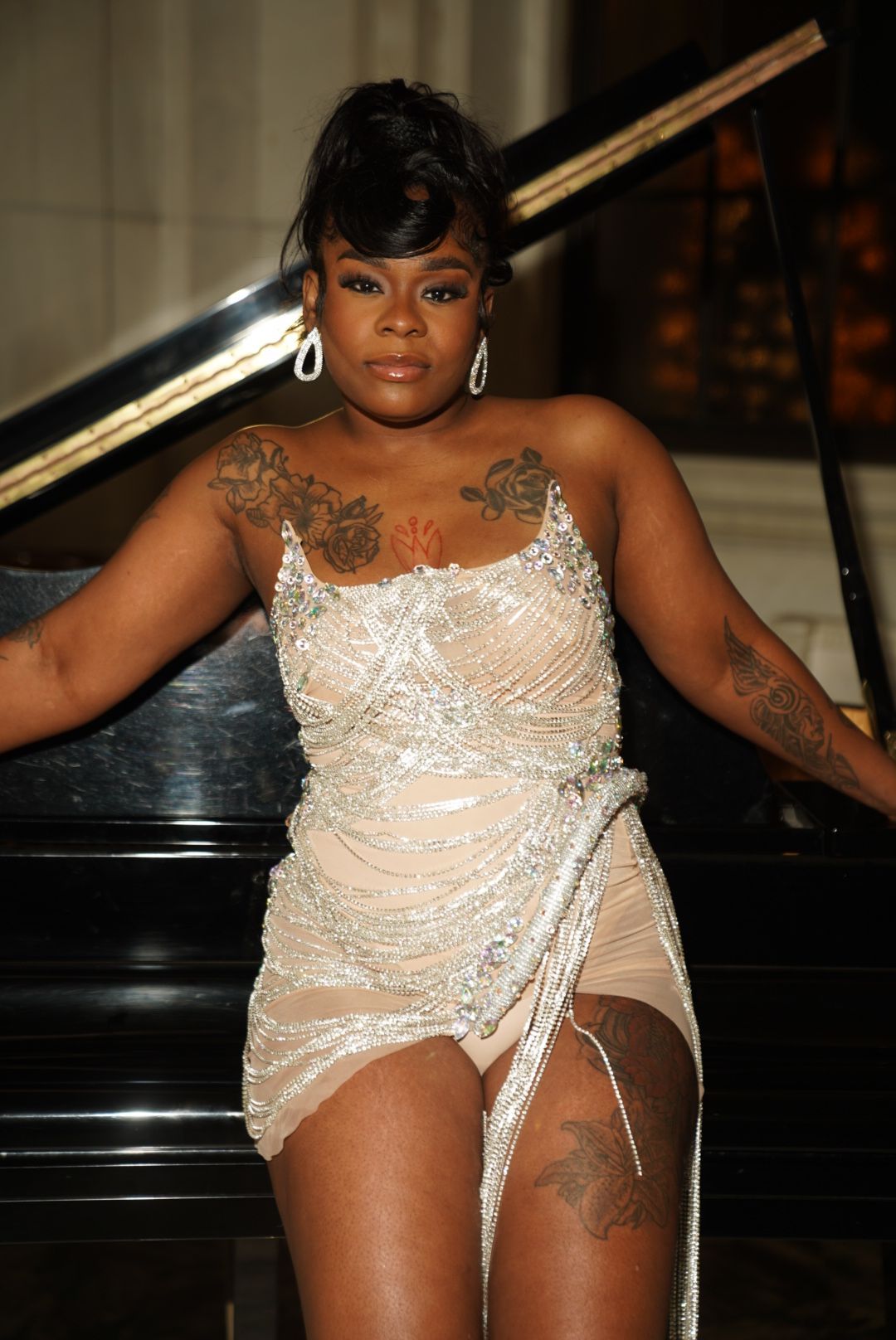 Person in an elegant plum-colored evening gown with crystal embellishments poses on white stairs with purple balloons.